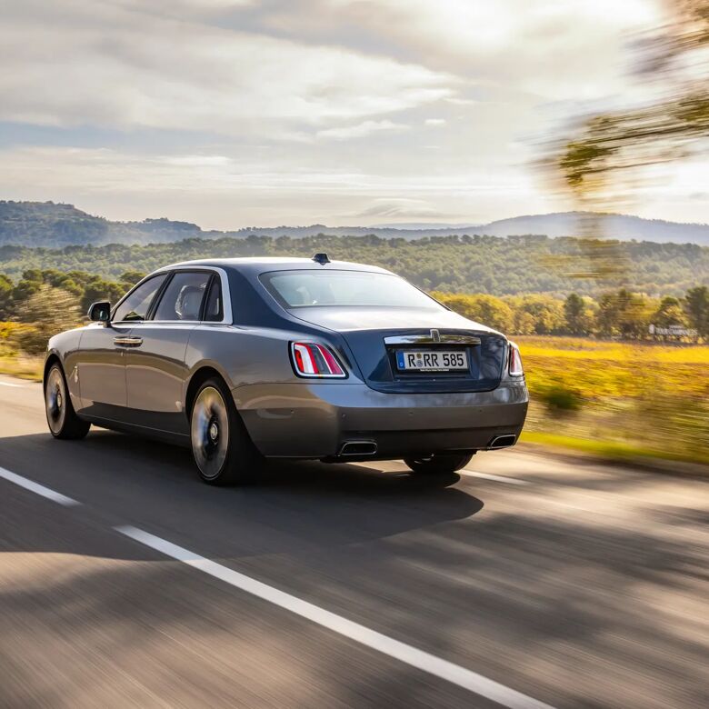 Zilvergrijze Rolls-Royce Ghost van achteren gefotografeerd met glooiend landschap op de achtergrond