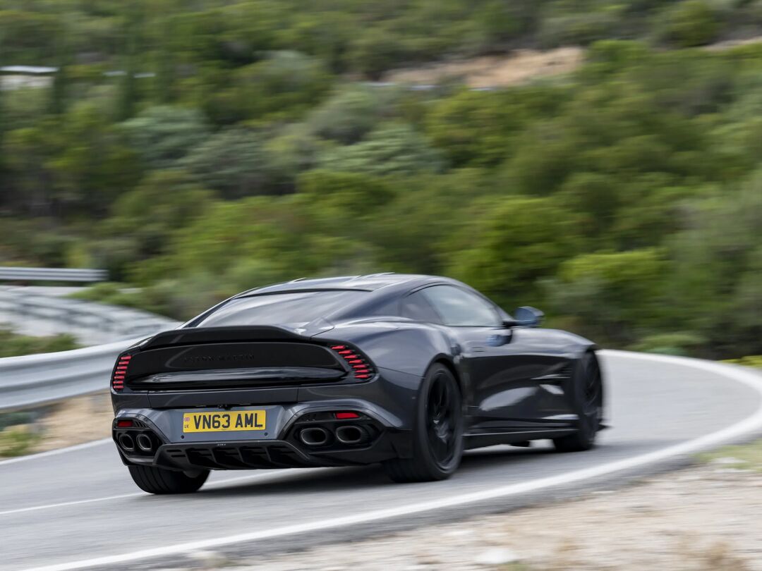 Zwarte Aston Martin Vanquish van achteren rijdend op een bergweg