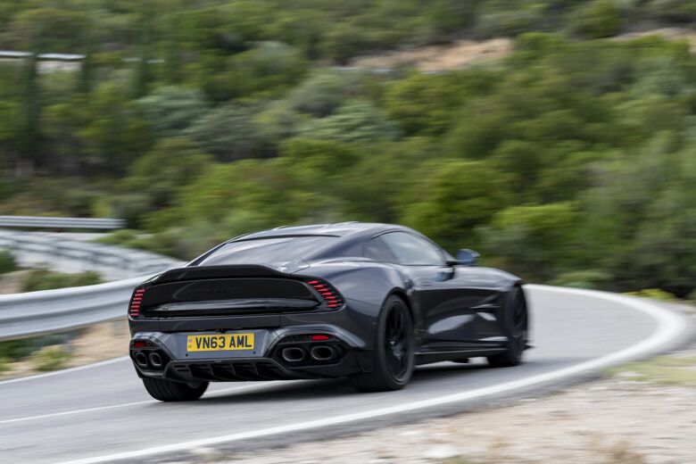 Zwarte Aston Martin Vanquish van achteren rijdend op een bergweg
