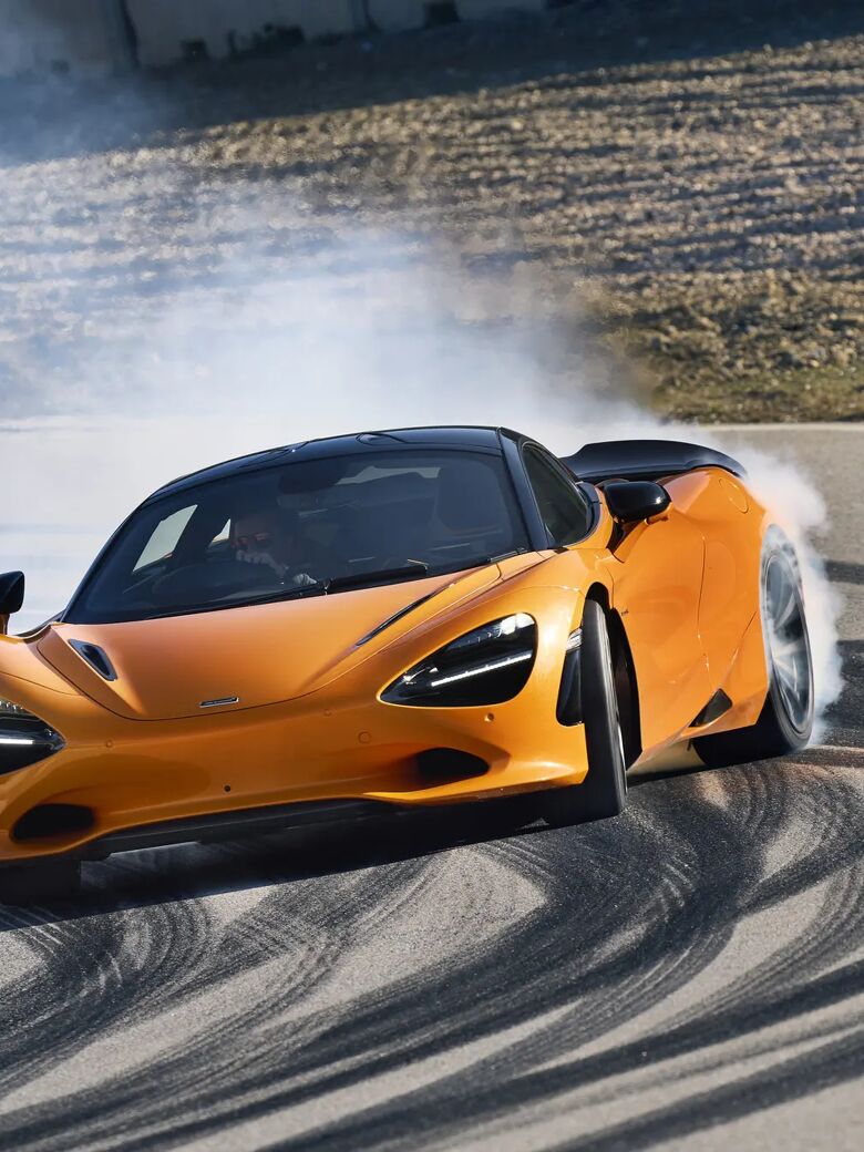 Oranje McLaren 750S Coupé maakt een burnout op het circuit met veel rook rond de voorwielen