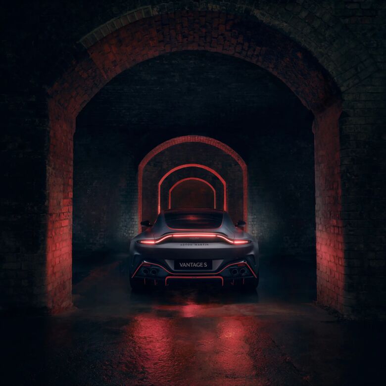 Achteraanzicht van de Aston Martin Vantage S onder een bakstenen boog met rode gloed