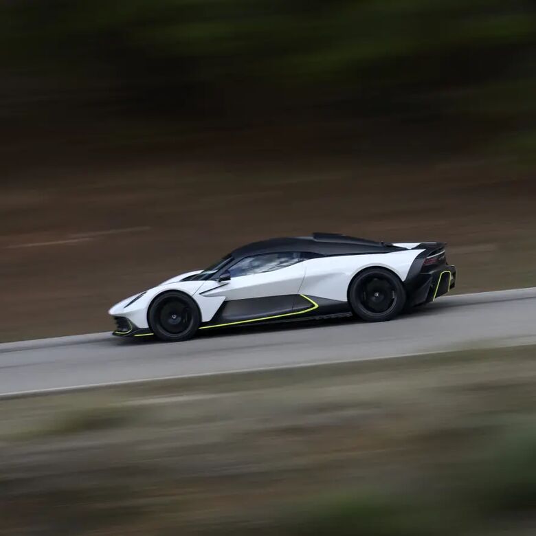 Aston Martin Valhalla rijdend, zijaanzicht tussen groen gebladerte