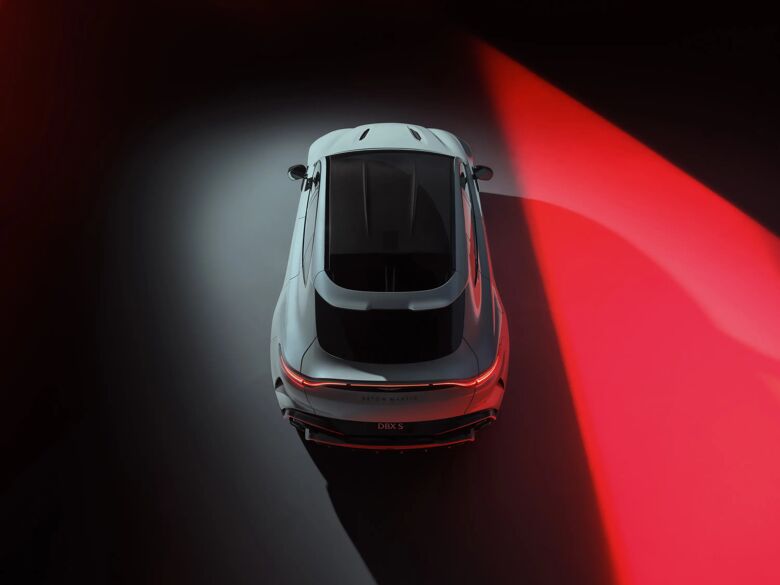 Witte Aston Martin DBX S recht van boven gezien in een studio met rode accenten