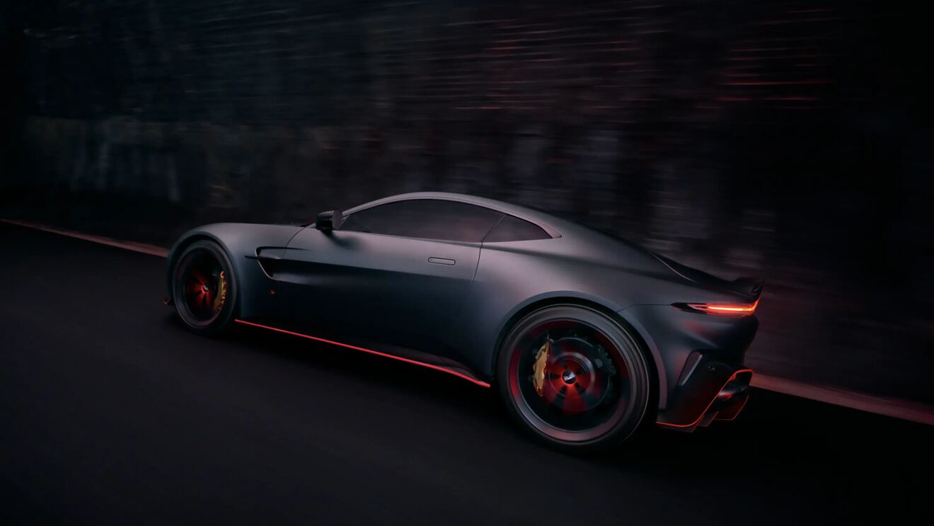 Zijaanzicht van de rijdende Aston Martin Vantage S met een rode accentlijn langs de onderzijde