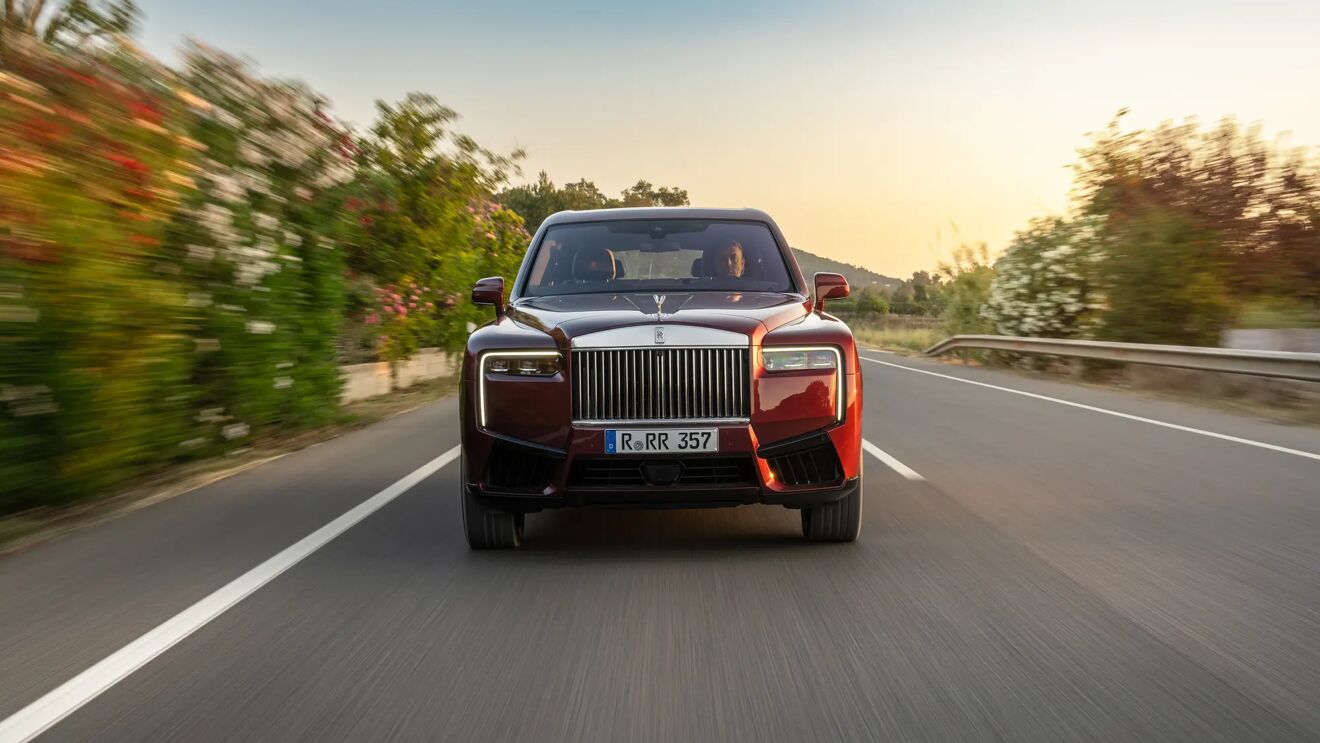 Rolls-Royce Cullinan in Scala Red rijdend op een landweg gefotografeerd van voren