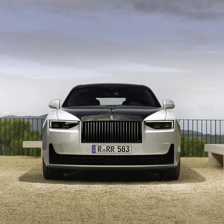 Rolls-Royce Ghost Black Badge frontaal geparkeerd bij een natuurstenen muur en zitbankjes.