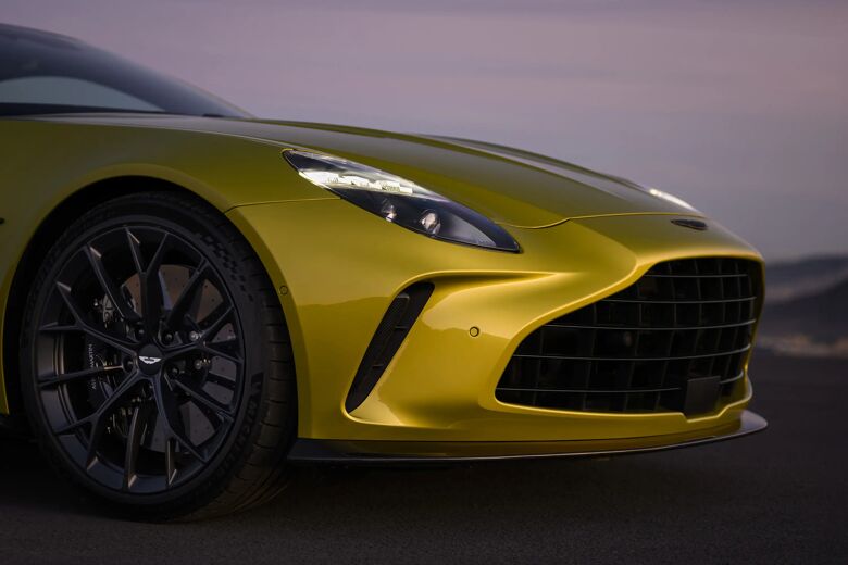 Gele Aston Martin Vantage in driekwart vooraanzicht met voorwiel en koplamp in de schemering